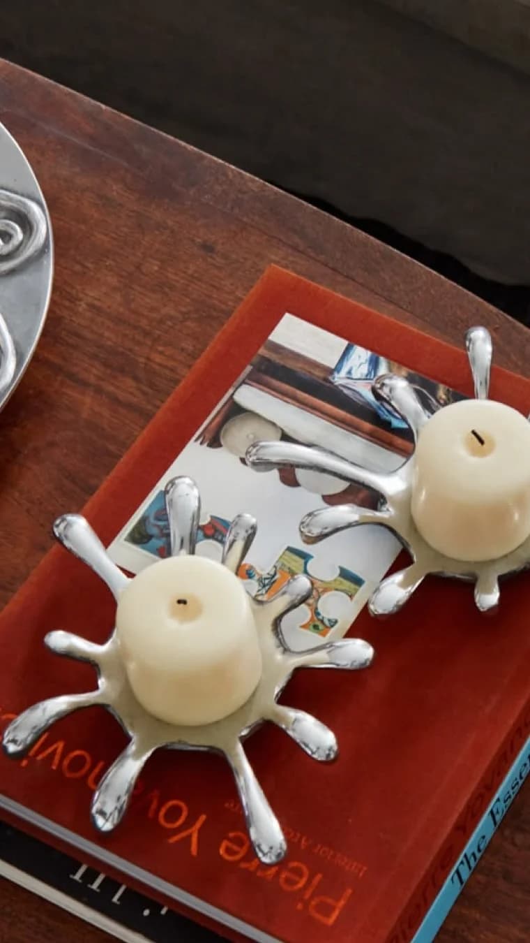 Instagram reel: two sculptural silver candle holders on a velvet book